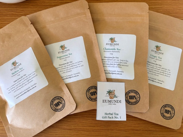 Four brown tea packages with white labels on a wooden surface, featuring the Eumundi Tea Co. brand.
