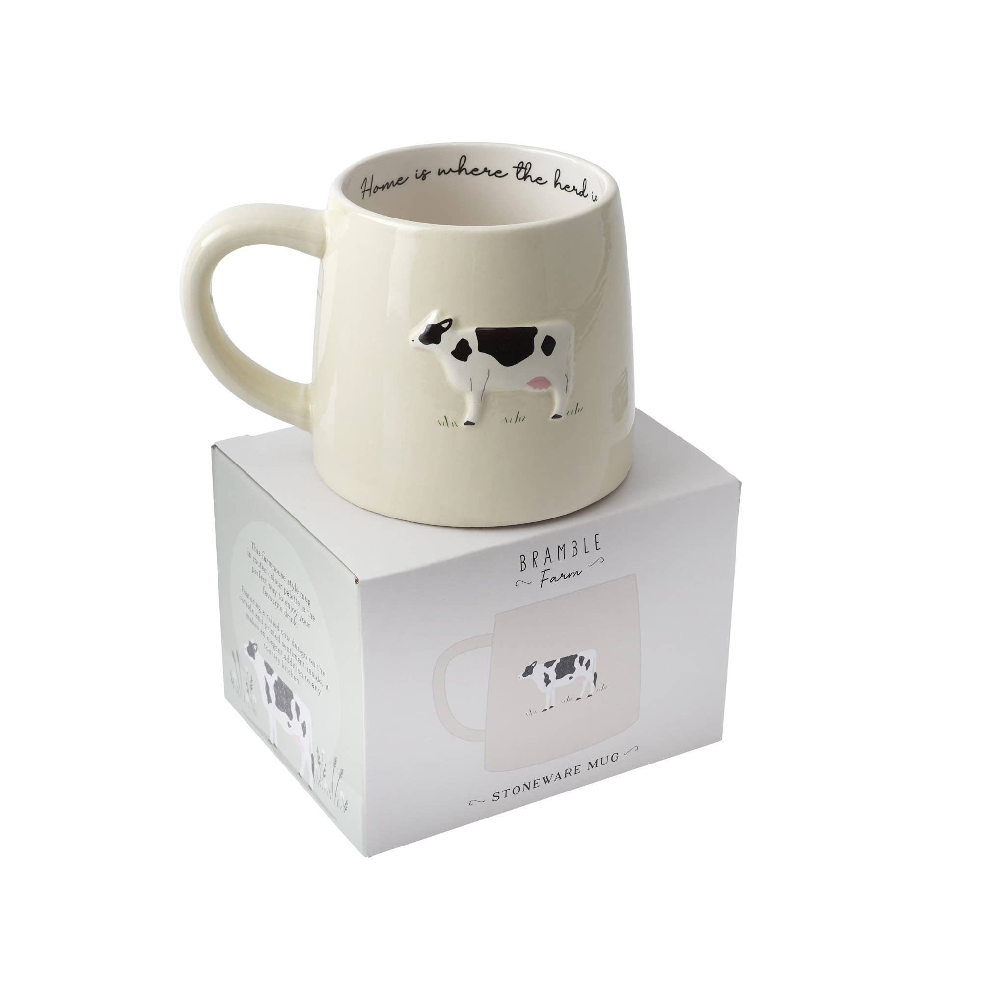 Ceramic mug with cow design and 'Home is where the heart is' text on a white background