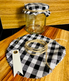 Glass jar with a checkered lid and ribbon on a wooden surface