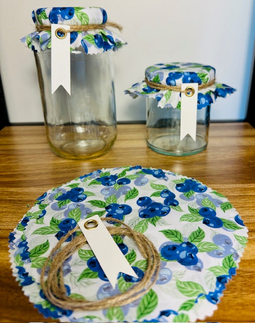 Set of glass jars with floral fabric covers on a wooden surface