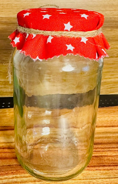 Glass jar with a red lid featuring white stars on a wooden surface