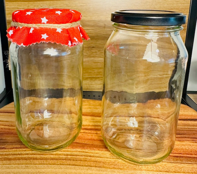 Two glass jars on a wooden surface, one with a red fabric cover and white stars, the other with a black lid.
