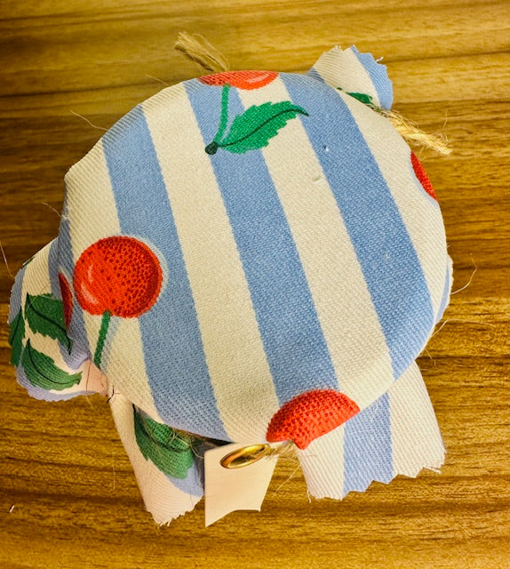 Fabric pouch with blue and white stripes and red floral patterns on a wooden surface