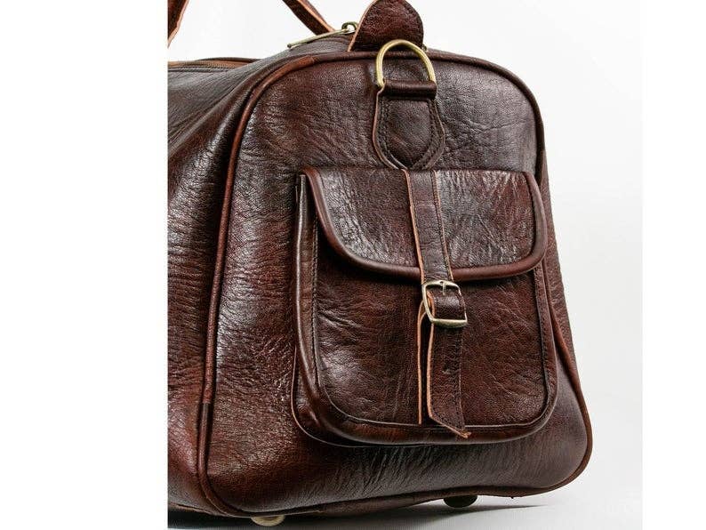 Brown leather bag with a strap on a white background