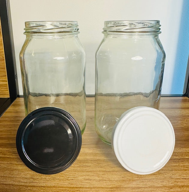Two clear glass jars with black and white lids on a wooden surface.
