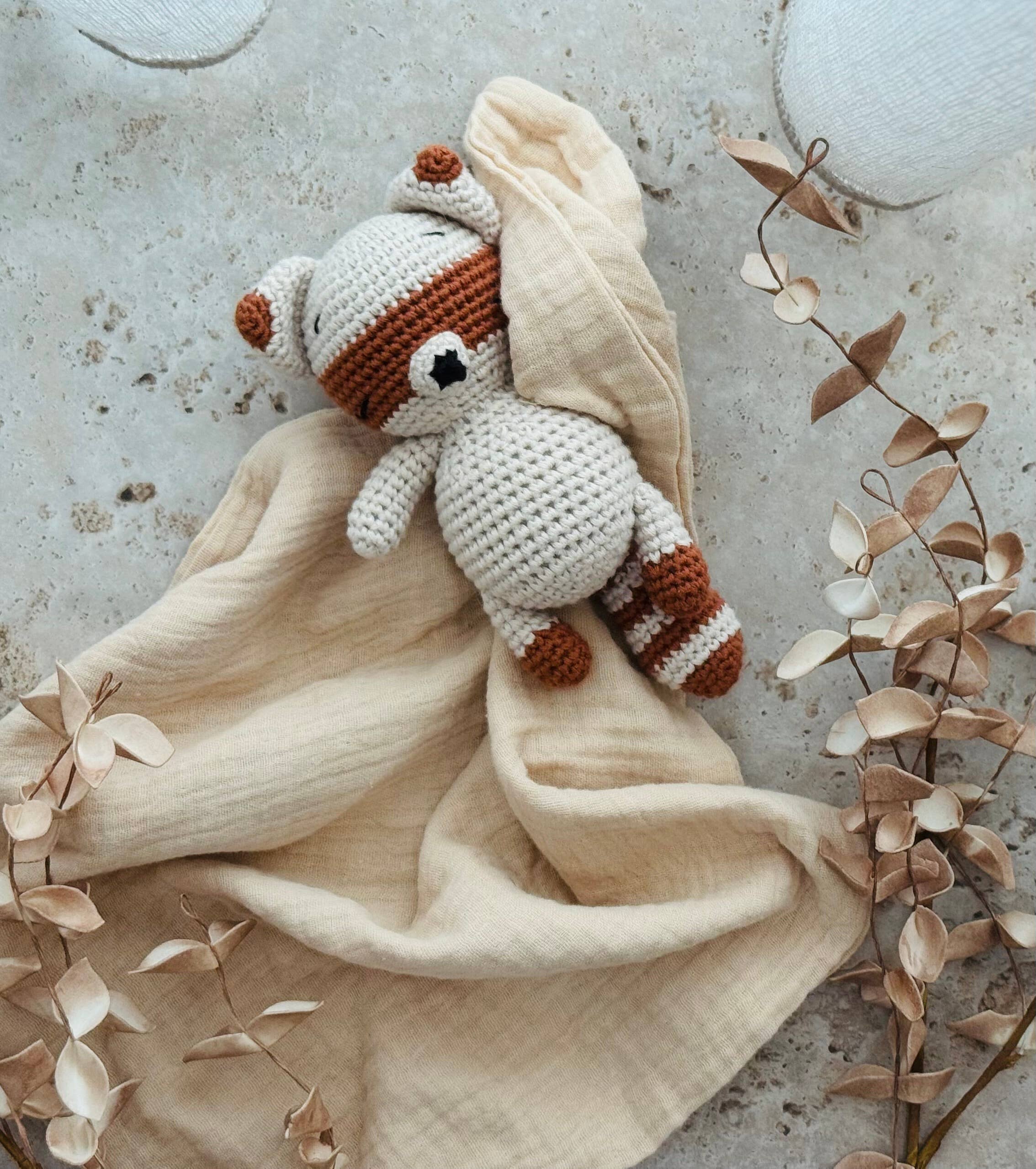 Crocheted animal plush toy on a beige blanket with decorative elements on a textured surface