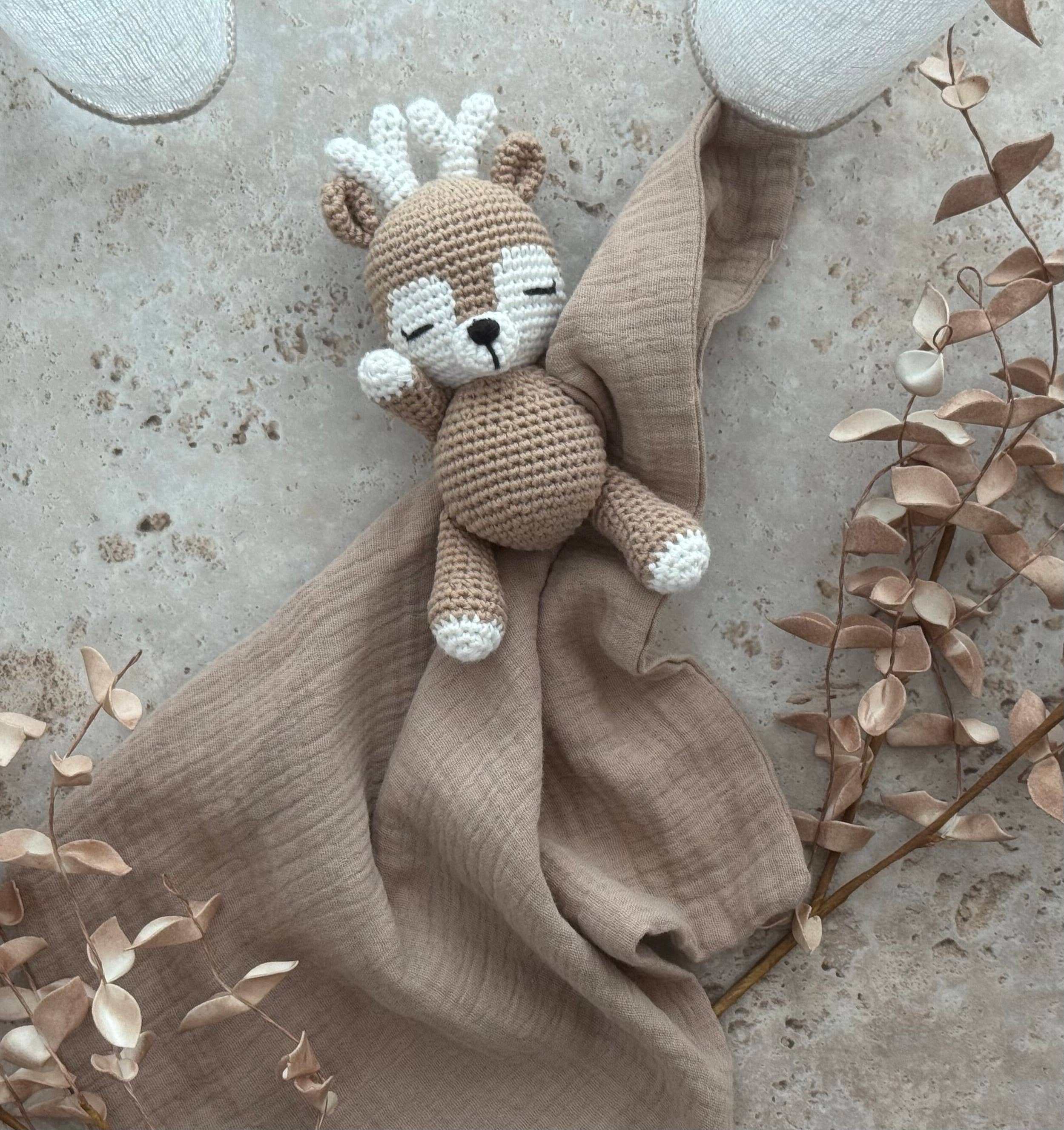 Knitted squirrel toy with a brown blanket on a textured surface with leaves.