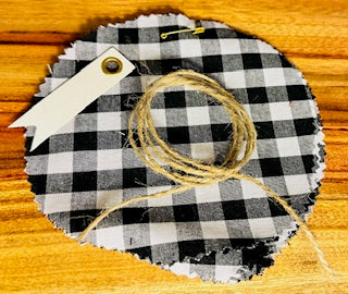 Black and white checkered fabric with twine and a tag on a wooden surface
