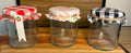 Three glass jars with decorative lids on a wooden surface