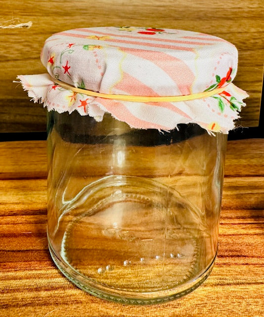 Clear glass jar with a floral fabric lid on a wooden surface