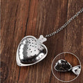 Heart-shaped metal tea infuser on a wooden surface with an inset showing tea leaves.