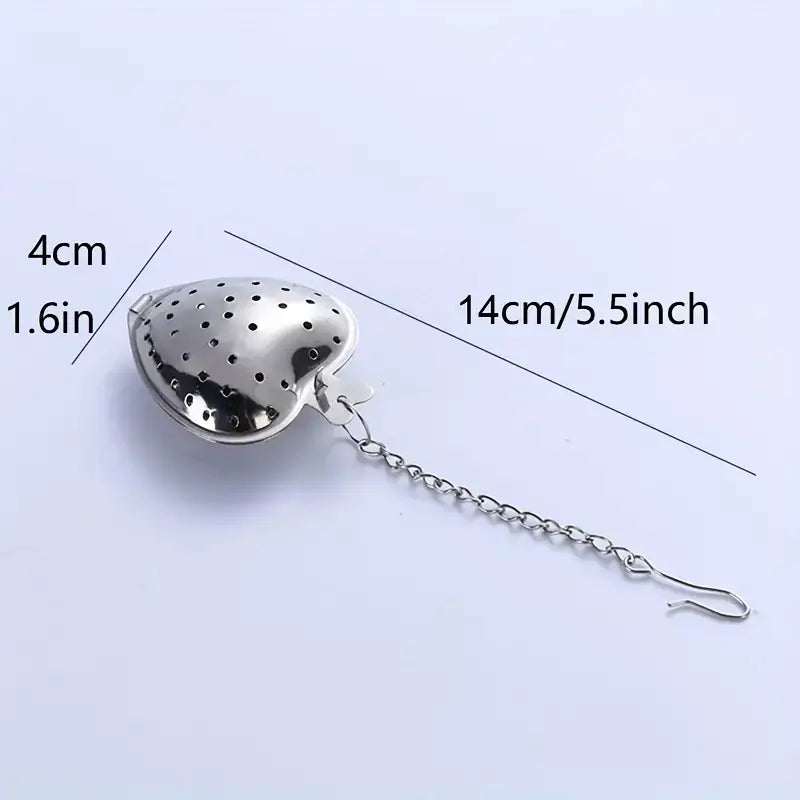 Stainless steel tea infuser with measurement labels on a light purple background